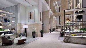 A modern hotel lobby with a central seating area, a reception desk, and a display of decorative items. - Burj View Studio Downtown (Dubai)