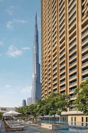 A modern building with a pool area, including lounge chairs and a swimming pool. - Burj View Studio Downtown (Dubai)