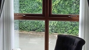 A room with a large window, a chair, and a small table with a book. - Sea Surf, 2 bedroom, fully equipped ground floor apartment, sleeps 4, in city (Bangor)