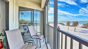 A balcony with a view of the beach, two chairs, and a table. - 🏖️Beachfront🌴Heated Pool, Hot Tub-Direct Beach Access-Land's End 10-303🌊 (Treasure Island)