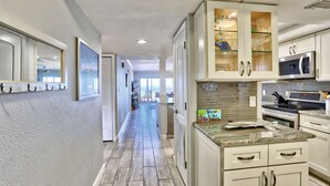 A modern kitchen with white cabinets, a granite countertop, and stainless steel appliances. - 🏖️Beachfront🌴Heated Pool, Hot Tub-Direct Beach Access-Land's End 10-303🌊 (Treasure Island)