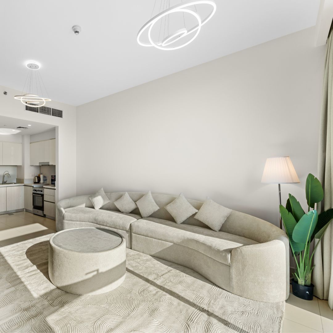 Een moderne woonkamer met een hoekbank, een ronde salontafel en een lamp.