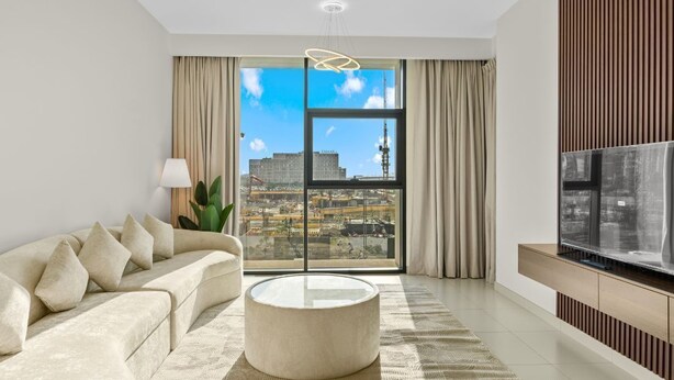 A modern living room with a sofa, coffee table, and a large TV.