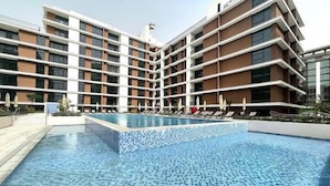A modern hotel with a large pool area, multiple floors, and a tiled pool deck.