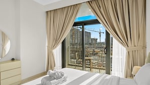 A hotel room with a large bed, a bedside table, a mirror, and a view of a construction site through the window.