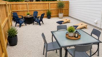 Un'area patio con tavolo e sedie, un molo in legno e vasi con piante.