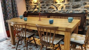 Ein Holztisch mit vier Stühlen, eine Steinwand im Hintergrund und Fliesen mit Muster.