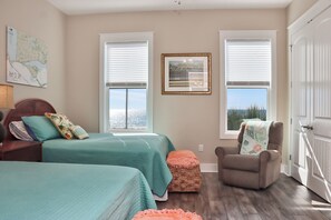 A bedroom with two beds, a chair, and a window with blinds.