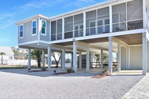 A two-story house with a covered patio and a gravel driveway.
