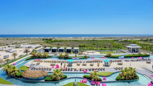 A resort with multiple swimming pools, sun loungers, and a view of the ocean.