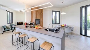Eine moderne Küche mit Kochinsel, Barhocker, Essbereich und Fernseher.