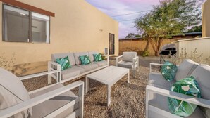Une terrasse extérieure avec un ensemble de canapés, des chaises blanches et une table.