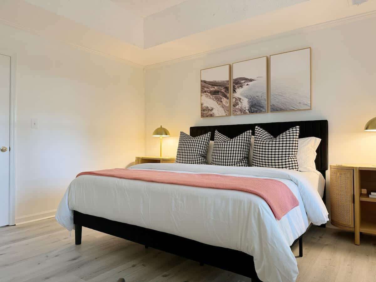 Une chambre à coucher avec un lit, une table de chevet, une lampe et un tableau accroché au mur.