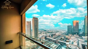 Un edificio alto con vistas a un paisaje urbano a través de una barandilla de balcón de vidrio.
