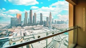 Vista panorámica de la ciudad desde un edificio alto con barandilla de vidrio.