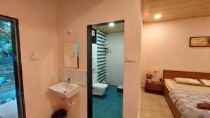 Quarto com uma cama, mesa de cabeceira e um criado-mudo. Inclui casa de banho com lavatório, sanita e chuveiro.