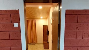 Um corredor com piso de azulejos que leva a um quarto com porta de madeira e cortina.