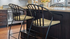 A kitchen with a central island, bar stools, a stove, and a window with a view.