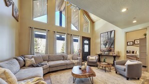 Ein geräumiges Wohnzimmer mit einer großen Eckcouch, einem runden Couchtisch und einem gemütlichen Kamin.