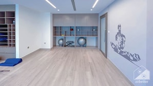 A modern room with a wooden floor, built-in shelving, exercise equipment, and a wall mural. - Luxurious Burj Royale One-bedroom & City Views (Dubai)