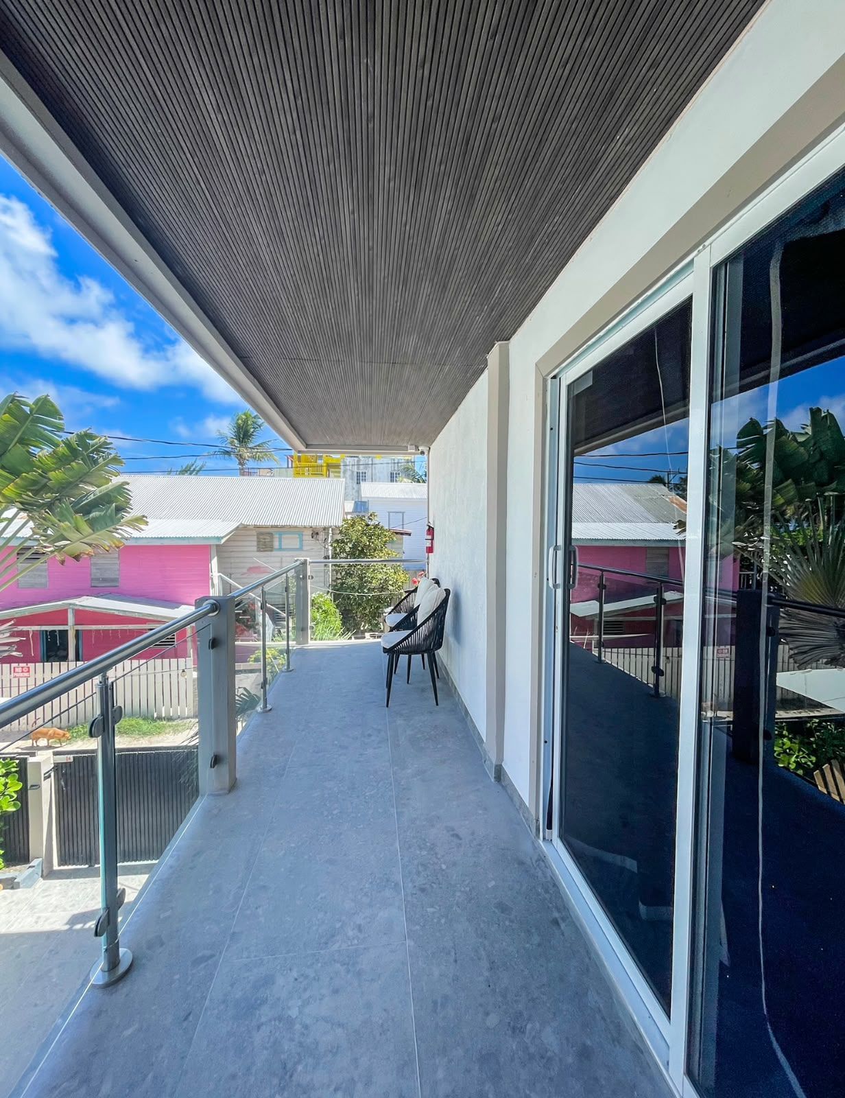 A balcony with a metal railing, a chair, and a glass door leading to an outdoor area.