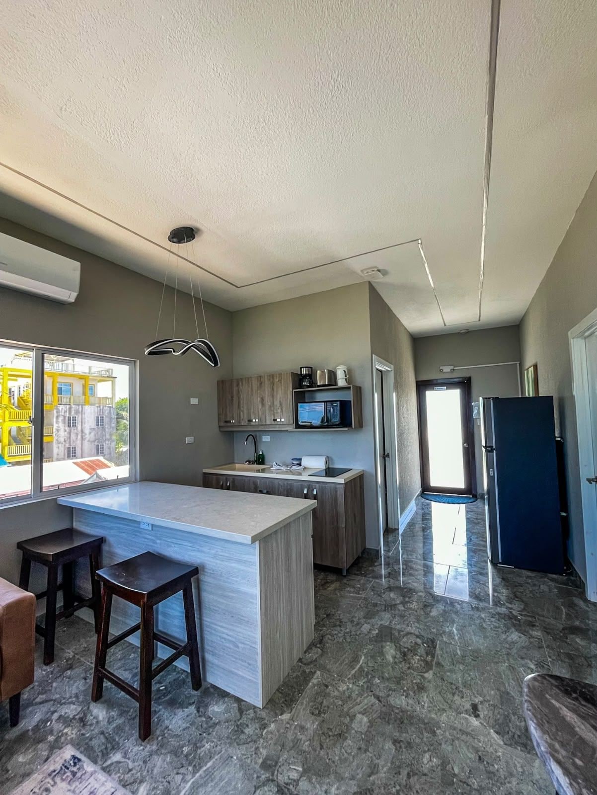 A modern kitchen with a central island, built-in appliances, and a view of the outside.