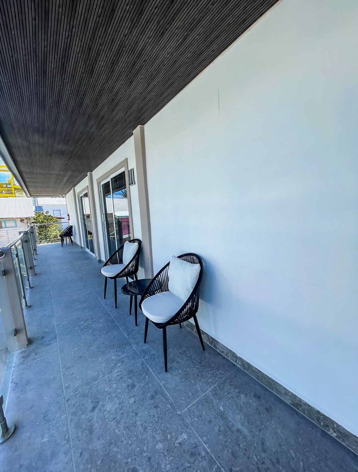 A covered outdoor seating area with chairs and a glass door entrance.