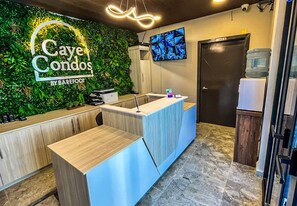 A reception desk with a green wall and a monitor above it. - Caye Caulker Condos By Barefoot (Caye Caulker)