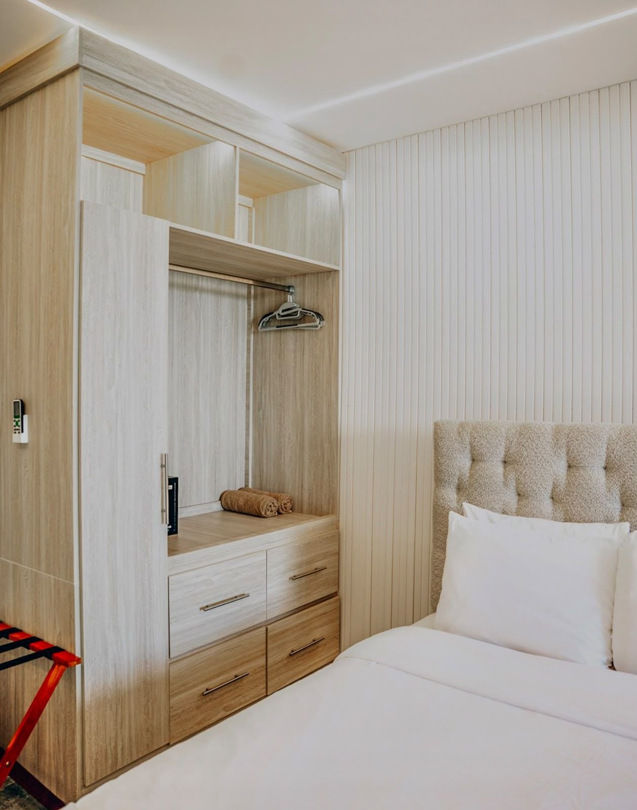 A bedroom with a bed, a wardrobe with a mirror, and a hanging garment rack.