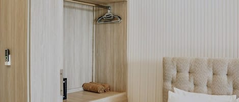 A bedroom with a bed, a wardrobe with a mirror, and a hanging garment rack.