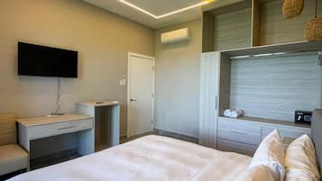 Une chambre d’hôtel moderne dotée d’un grand lit, d’un téléviseur à écran plat fixé au mur, d’un bureau avec une chaise et d’une armoire.