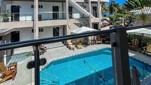 A multi-story hotel with a swimming pool and outdoor seating area. - Caye Caulker Condos By Barefoot (Caye Caulker)