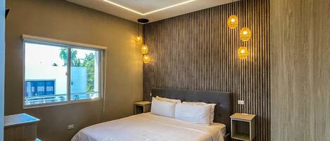 A modern bedroom with a large bed, bedside tables, a window, and a patterned rug.