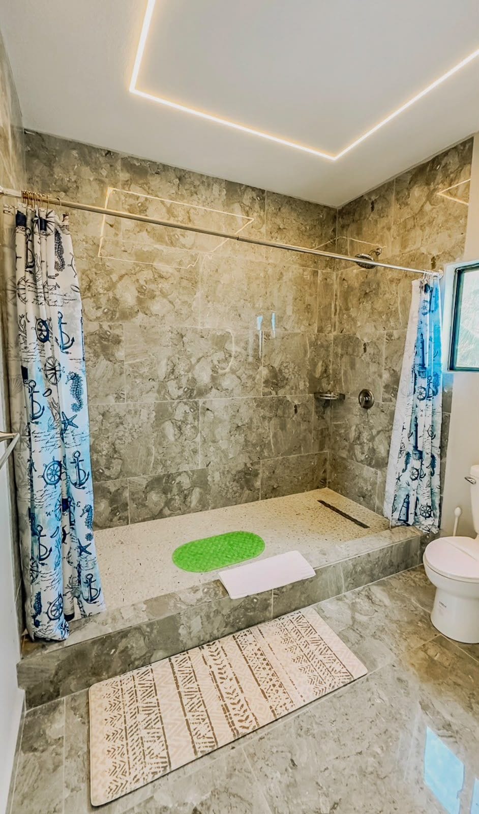 Ein Badezimmer mit Dusche, Toilette und Marmorboden.
