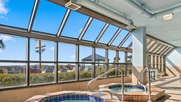A rooftop pool area with two hot tubs, large windows, and a clear view of the surrounding landscape. - Phoenix V Beachfront Family Condo with Pool and Gulf Views (Orange Beach)