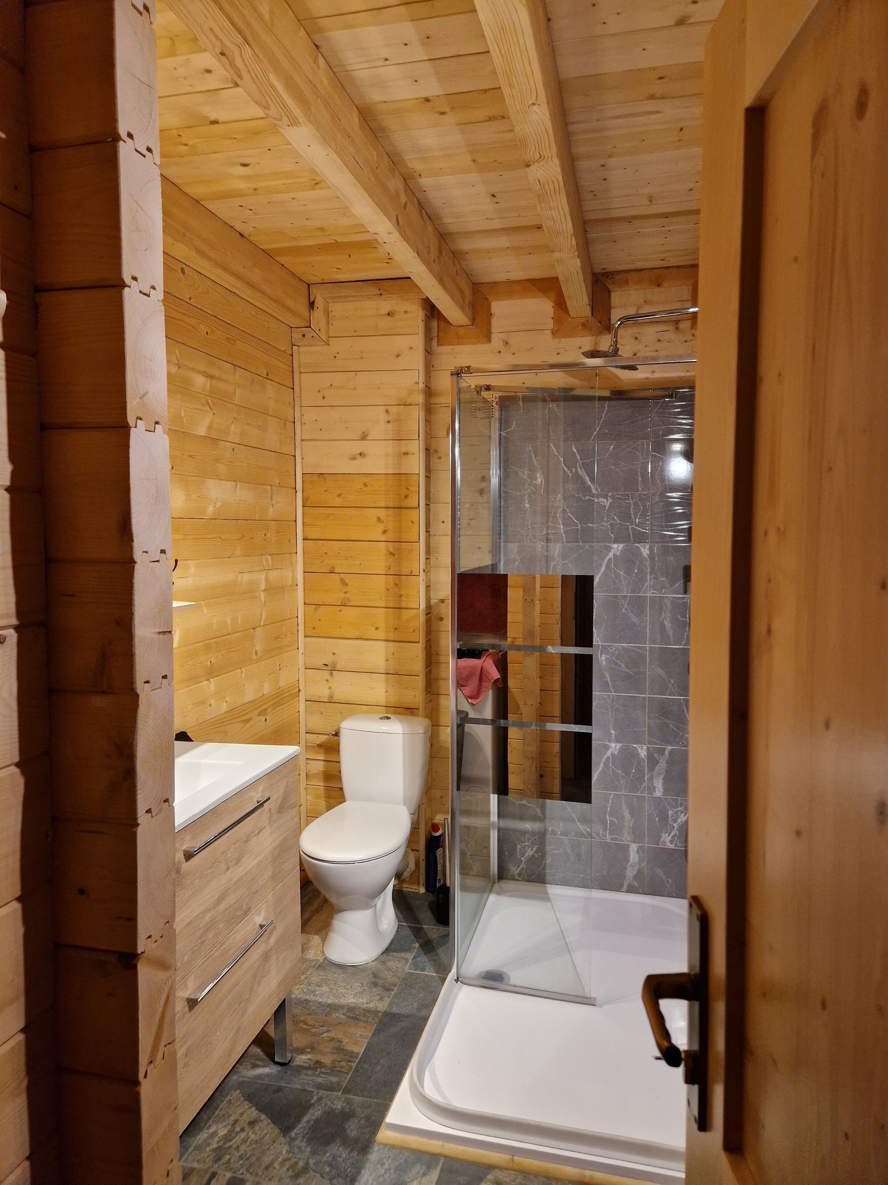 Een houten badkamer in een vakantiebungalow, met toilet, wastafel en douche.