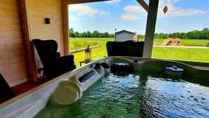 A hot tub with a view of a green field and a small building. - Cottage the Bird's Nest with jacuzzi (Oldekerk)