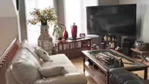 Een woonkamer met een bank, een salontafel, een televisie en een open haard.