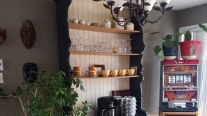 Een keuken met een houten aanrecht, een koffiezetapparaat, een waterkoker en een plank met glazen en kommen.