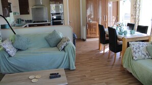 Un espacio habitable compacto con sofá, mesa de comedor y kitchenette.