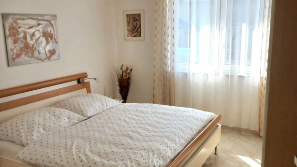 Une chambre à coucher avec un lit, une fenêtre avec des rideaux et un tableau au mur.