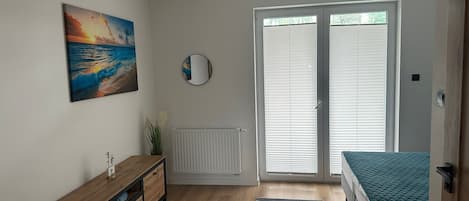 A bedroom with a bed, a dresser, a painting, a mirror, and a window with blinds.
