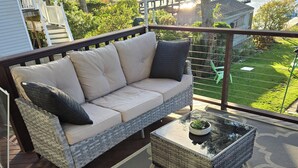 Een overdekt terras met een rieten zithoek, inclusief een rieten fauteuil en een salontafel.