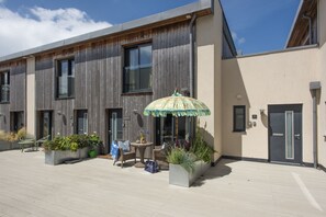 A modern building with large windows, outdoor seating, and planters.