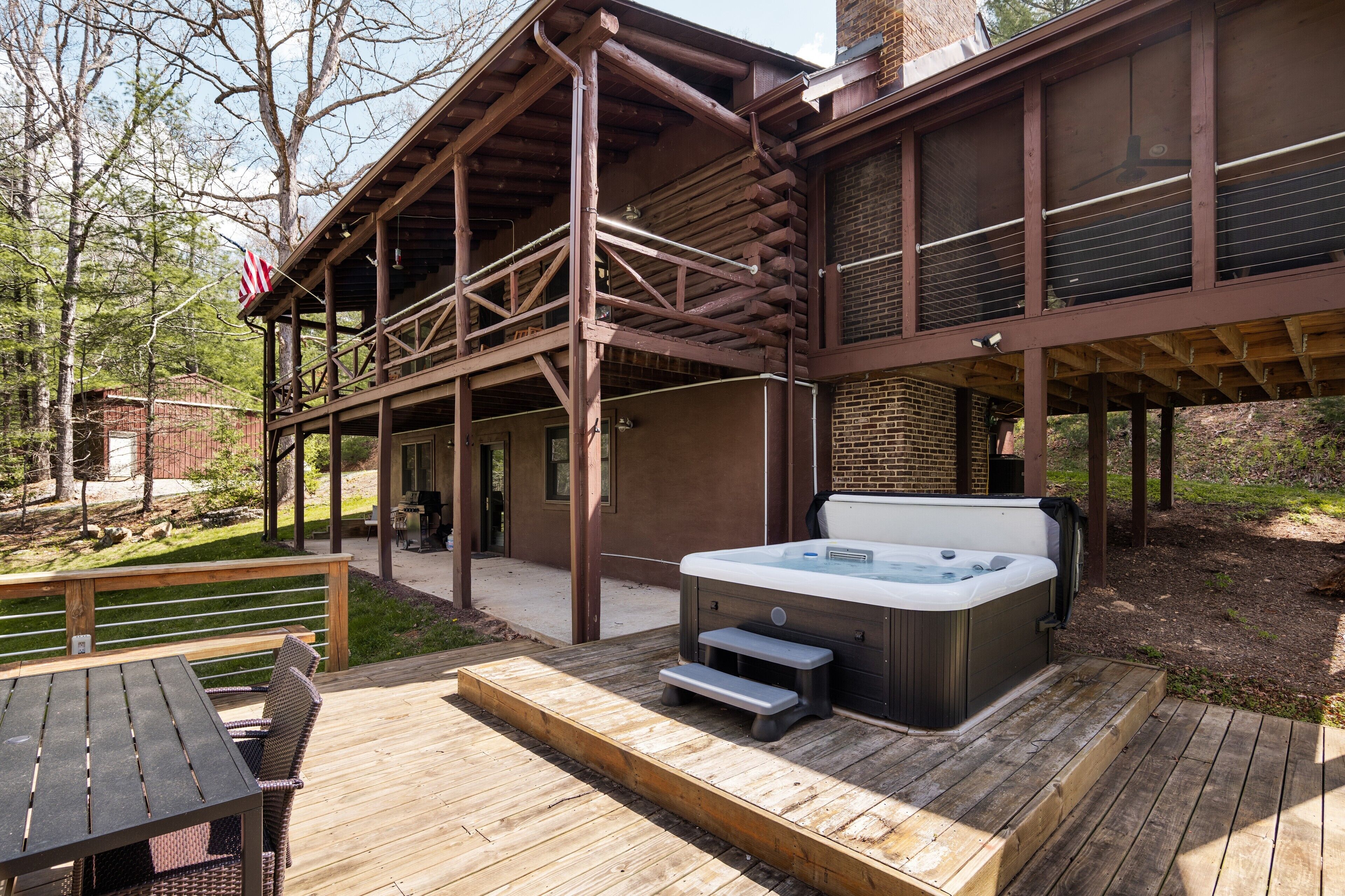Eine Holzterrasse mit Whirlpool, Sitzgelegenheiten im Freien und einer überdachten Veranda.