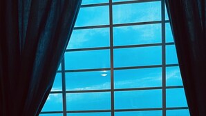 Ein Fenster mit Blick auf das Meer durch ein Gittermuster.