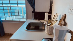 Eine kleine Küche mit Spüle, Kaffeemaschine und Herd.