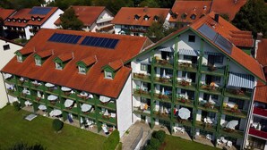 A multi-story hotel with balconies, solar panels, and outdoor seating areas.
