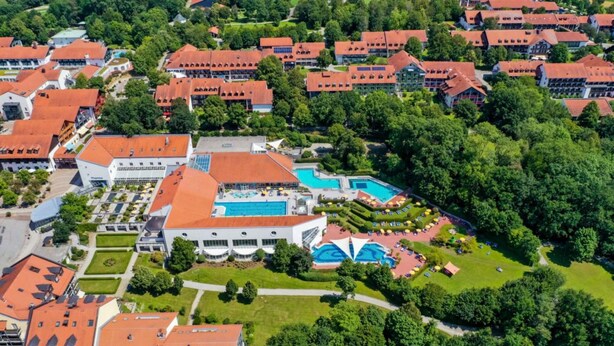 An aerial view of a resort with multiple buildings, a swimming pool, and landscaped gardens.