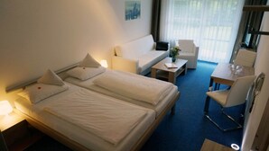 A hotel room with two beds, a sofa, a dining table, and a chair.